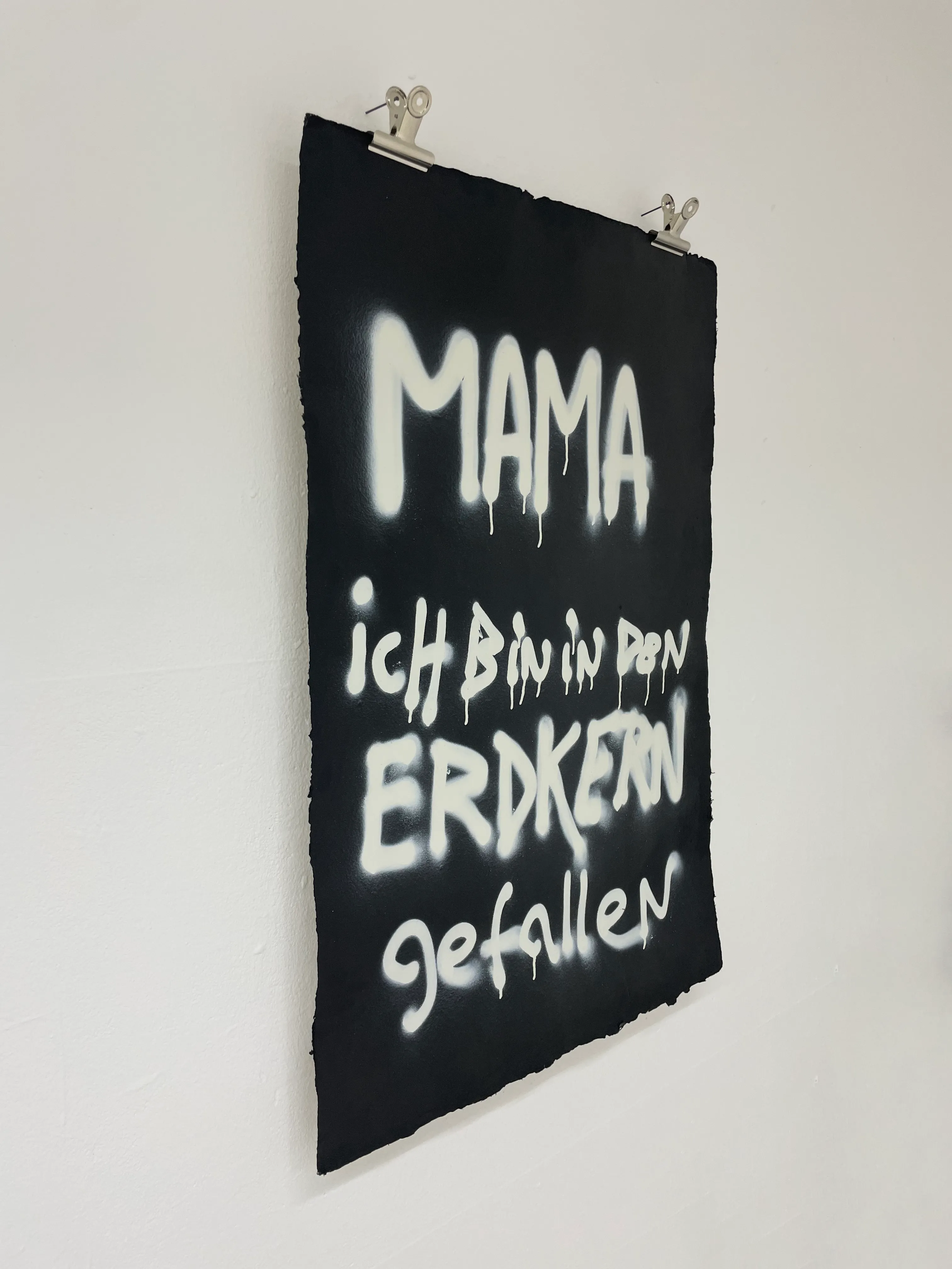 Side view of the artwork held by metal clips hanging on nails